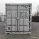 A shipping container with capacity details and markings, set against an industrial backdrop.
