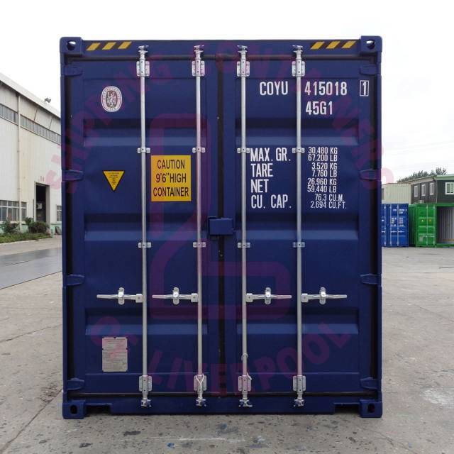 A blue shipping container with labels, details, and caution signs, set against a warehouse backdrop.