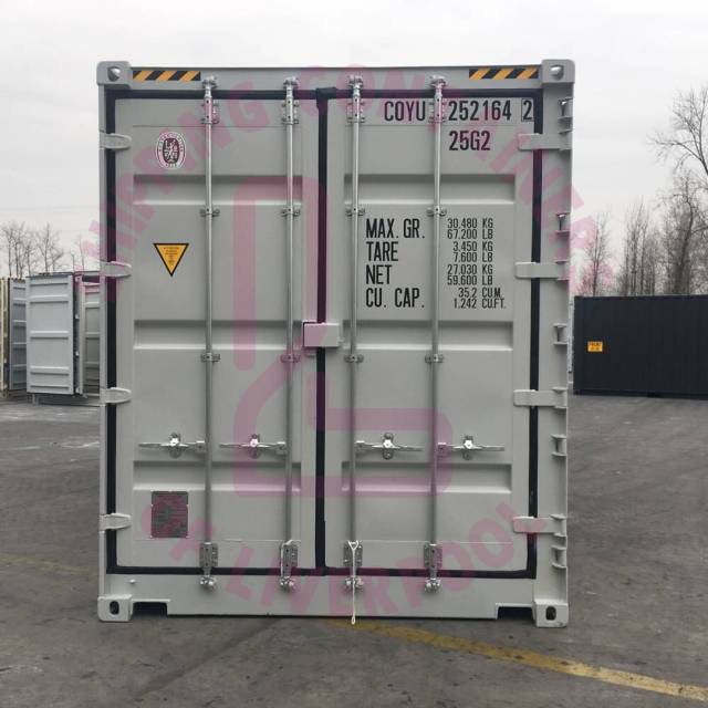 A shipping container with capacity details and markings, set against an industrial backdrop.