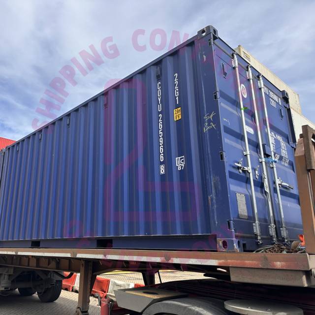 A blue shipping container on a truck with a cloudy sky background and overlay text about Liverpool.